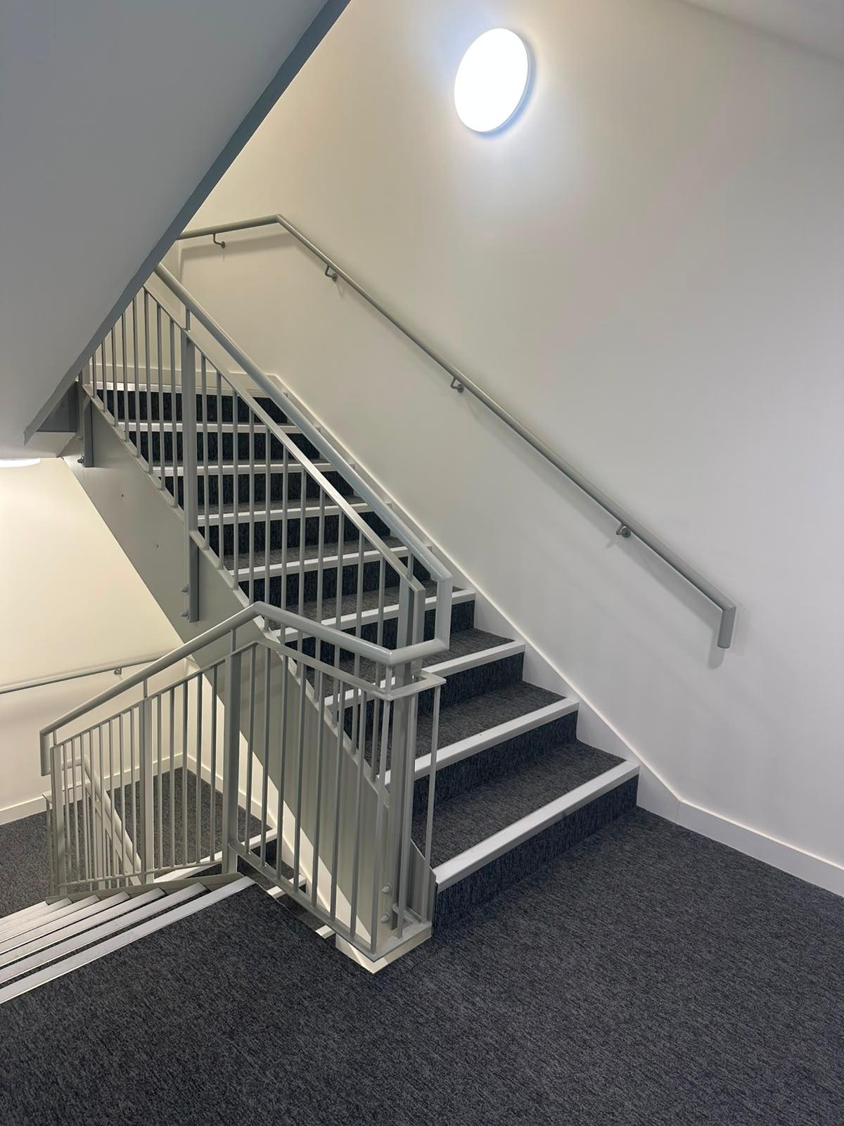 Grey painted stair balustrade and handrail to a commercial stair core