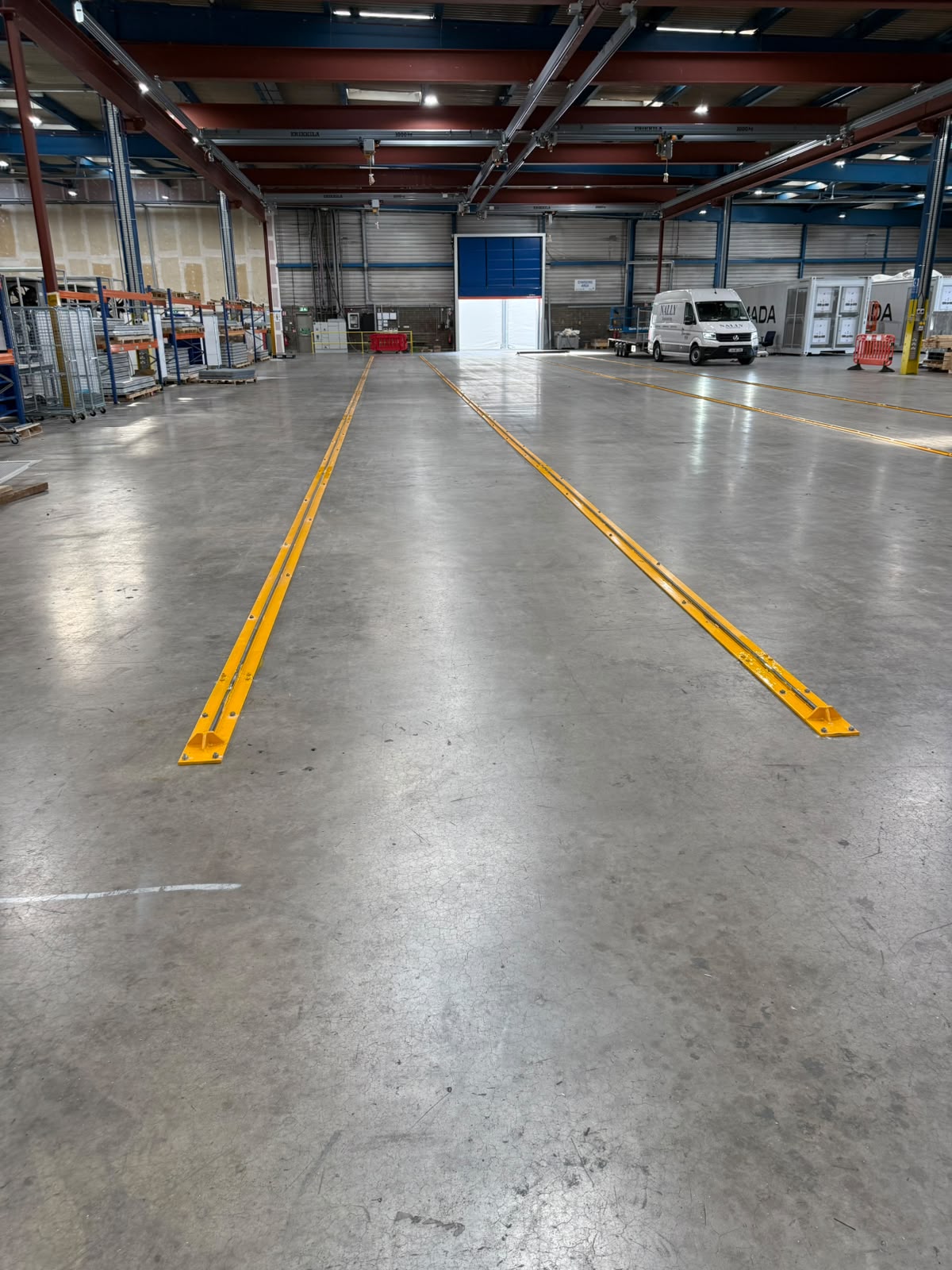 Two long runs of yellow guide rail set into a polished concrete factory floor