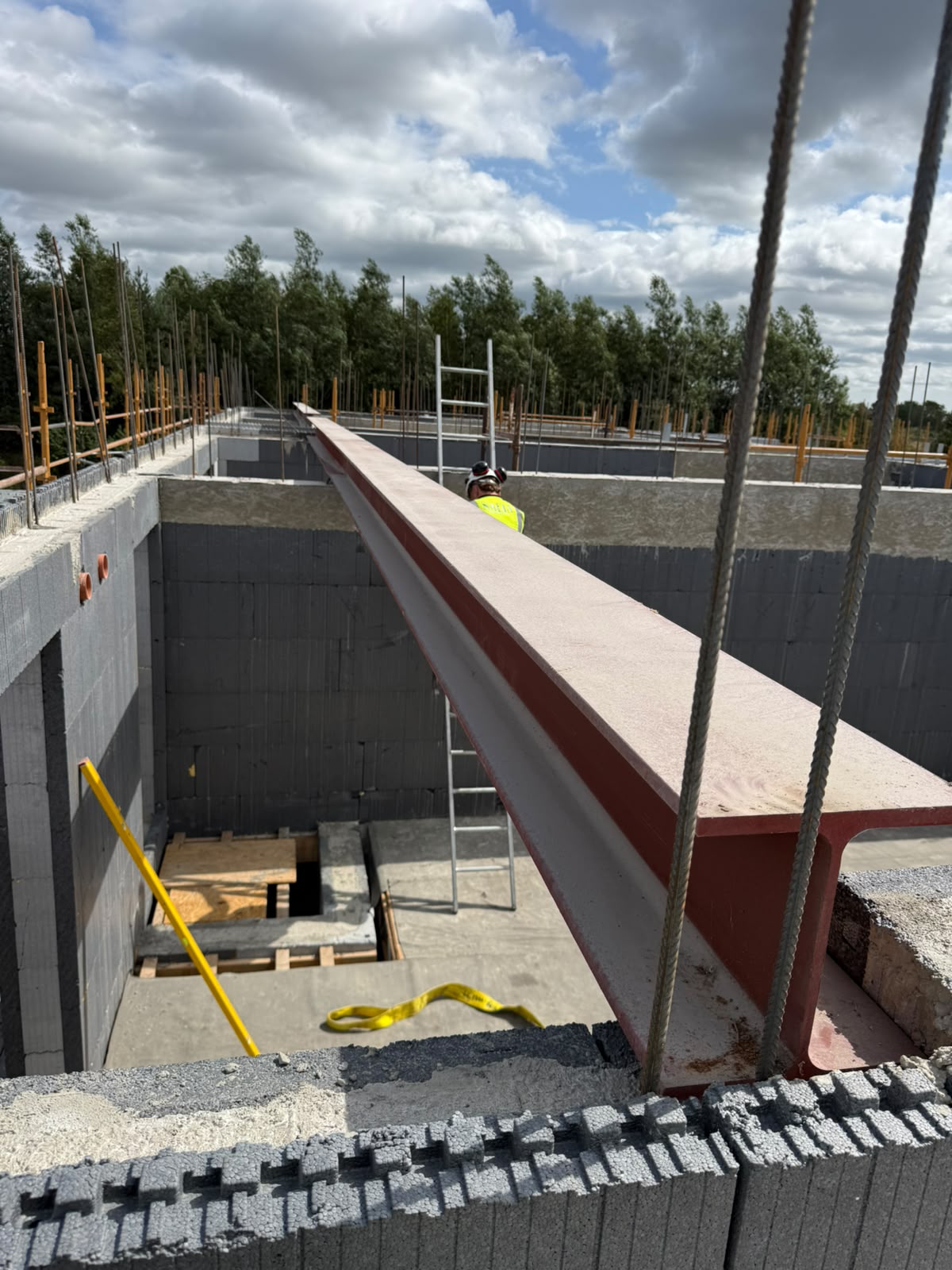 Long red oxide steel beam landed across blockwork walls over a basement on a new build site