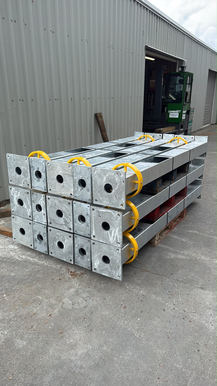 Stacked galvanised steel fabricated units with yellow hoops on pallets outside the Nally Engineering workshop