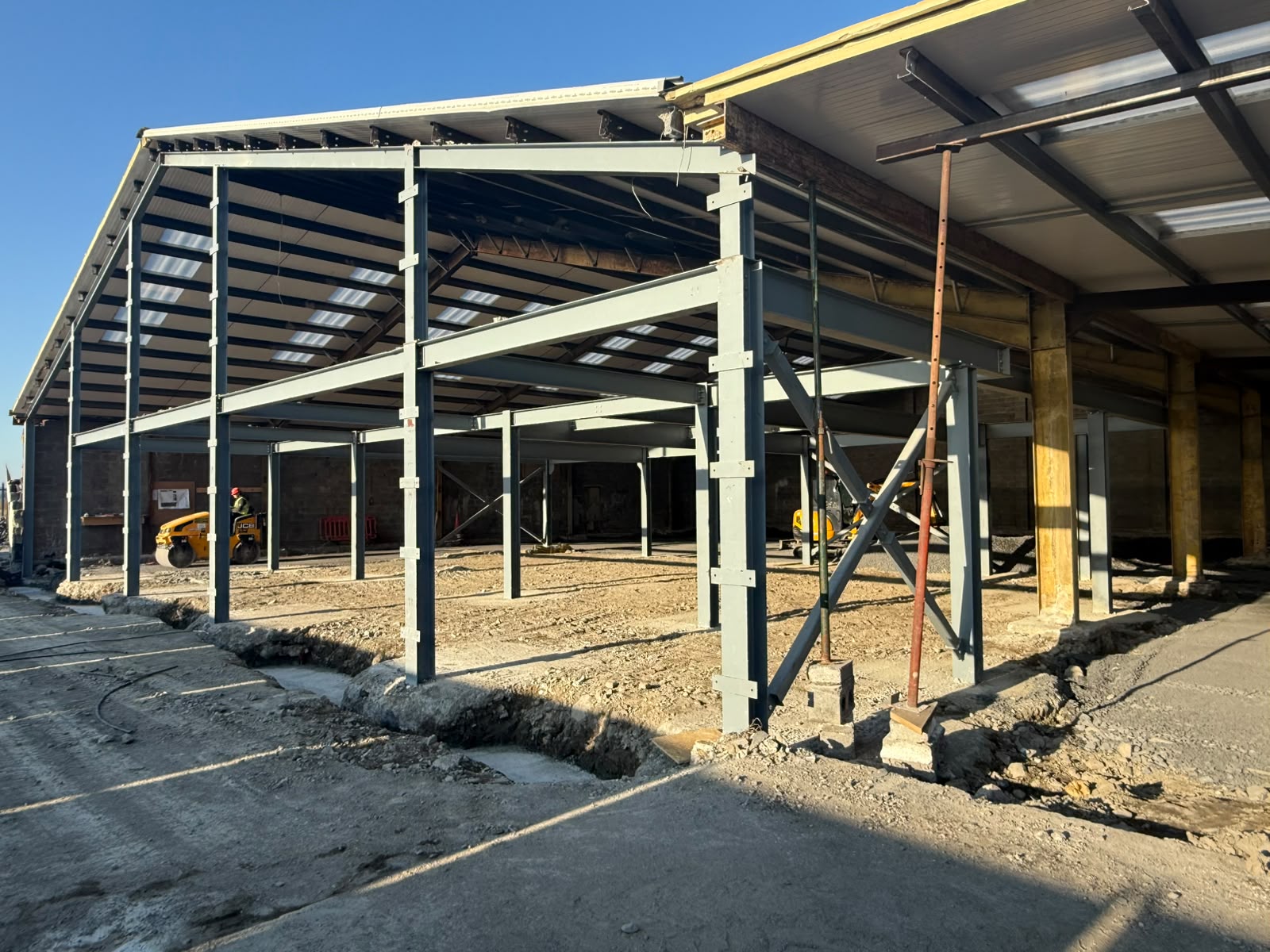 End view of the grey steel frame extension showing columns, bracing and temporary props on pad foundations