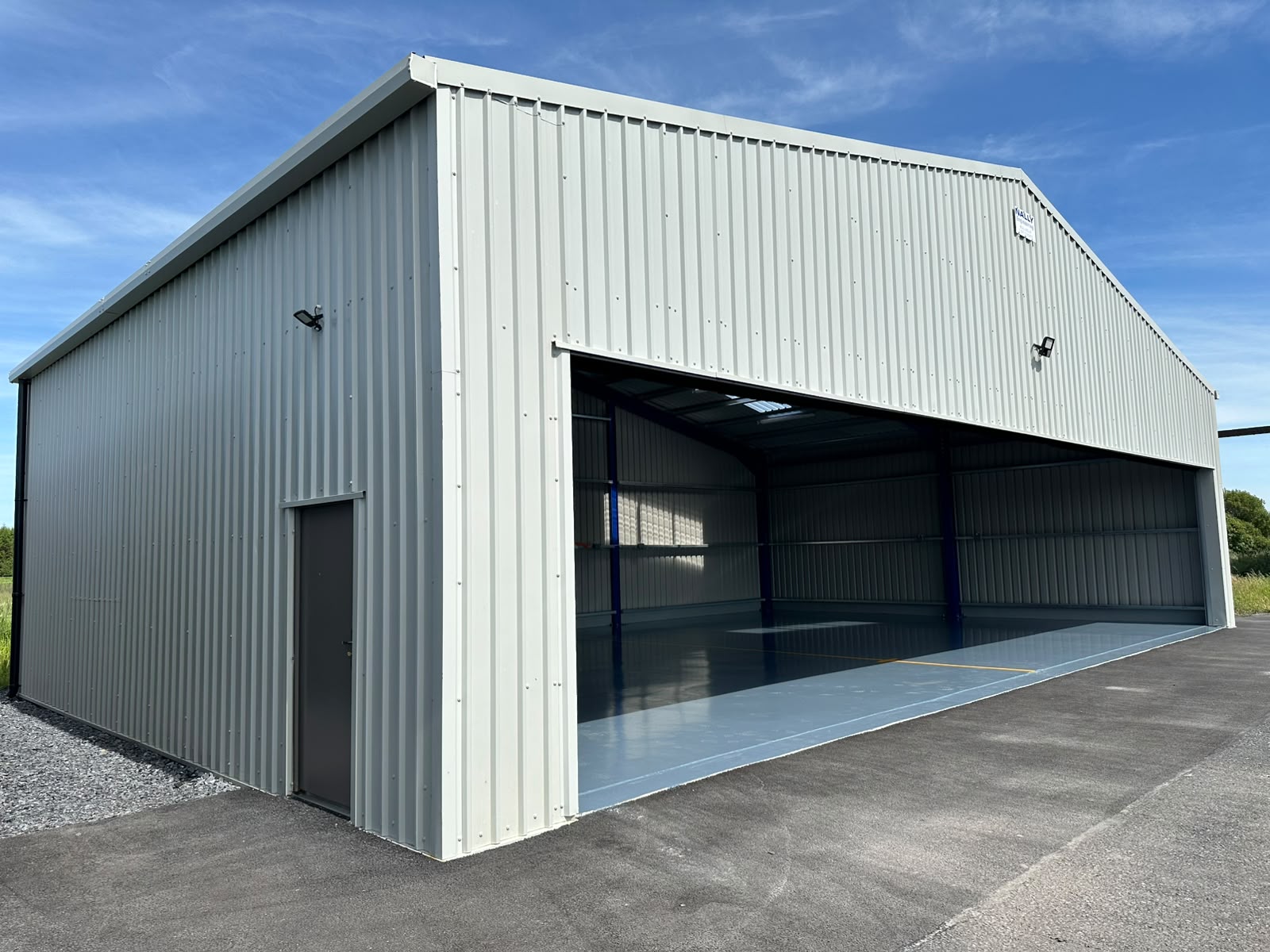Finished pale grey clad hangar with a wide open door bay, personnel door and new apron