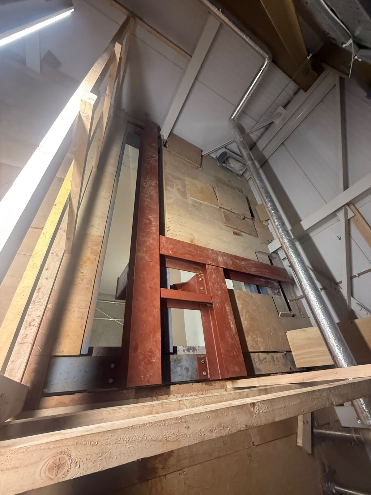 Red oxide painted steel frame forming a goods lift shaft inside an existing building