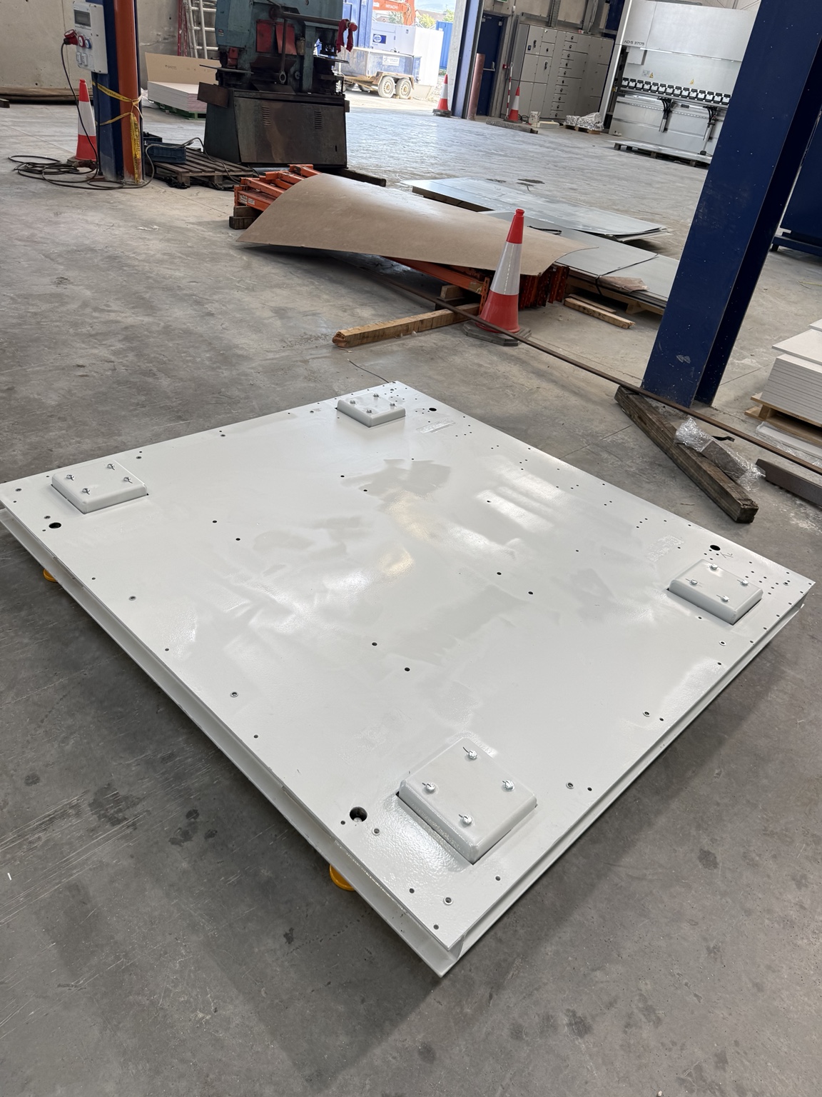 Finished painted precision steel skid deck with machined mounting pads on the workshop floor