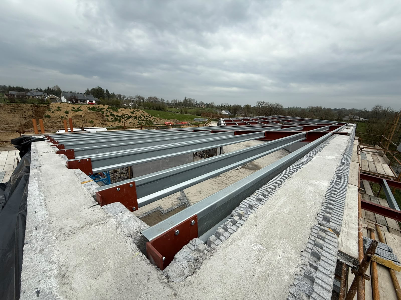 Galvanised steel floor joists bolted to red oxide beams spanning a new build ground floor in open countryside