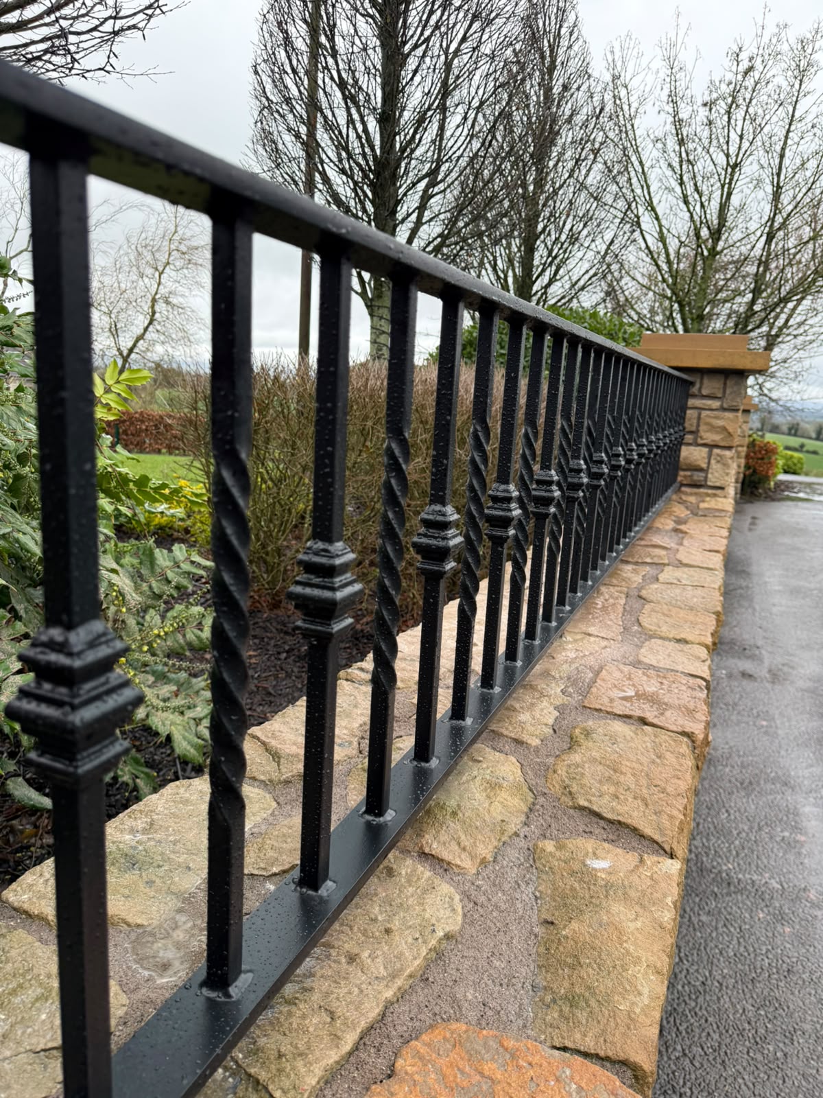 Decorative steel boundary railing fixed to a stone boundary wall