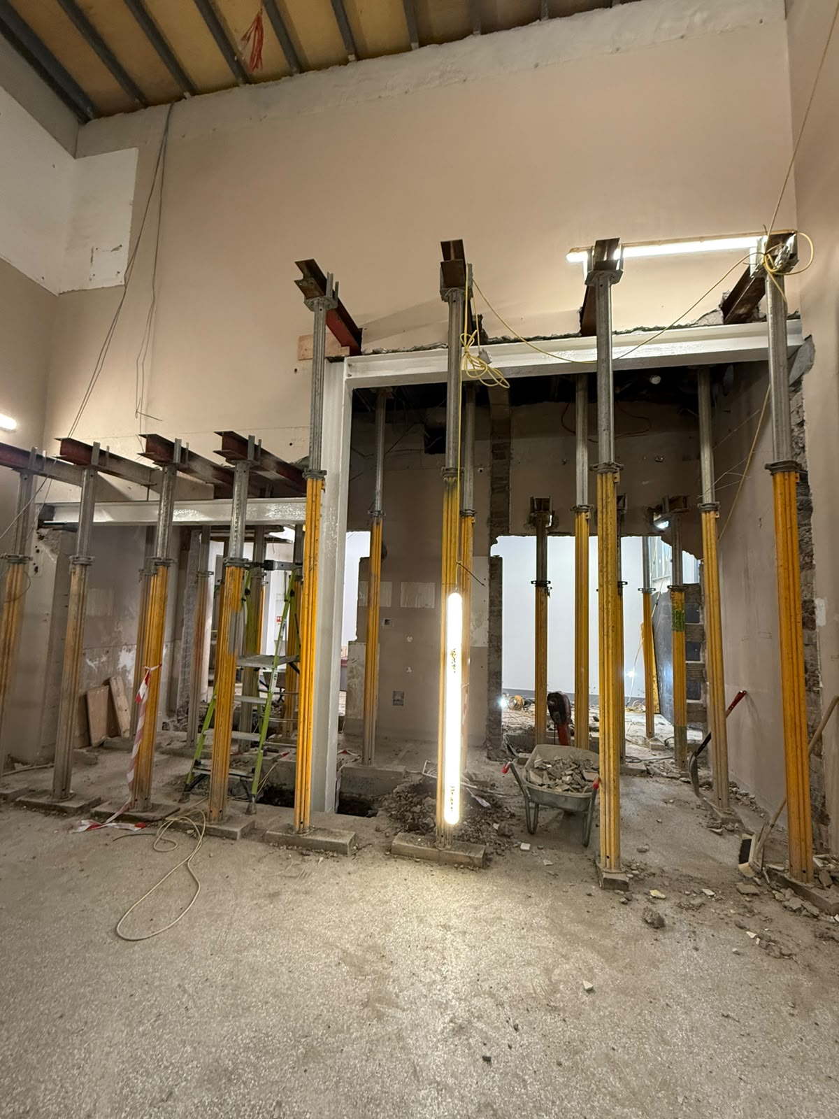 Adjustable props and steel beams supporting several new openings through internal walls during a fit out